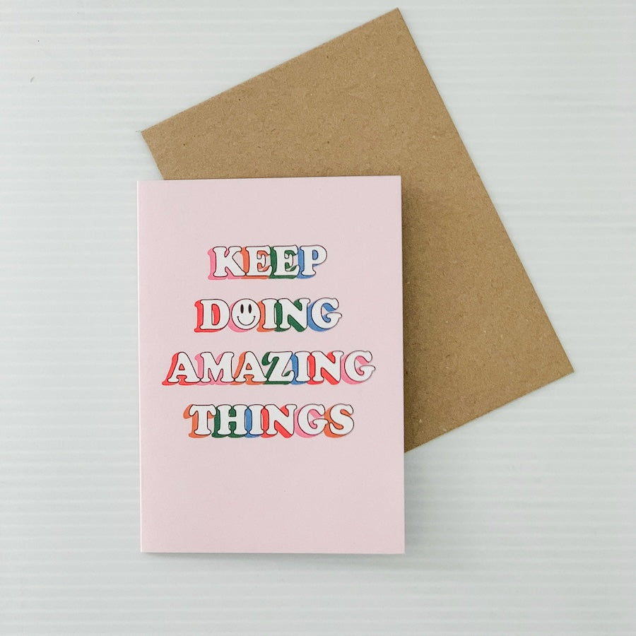 Pink card with 'Keep Doing Amazing Things' text and a brown envelope on a light gray background