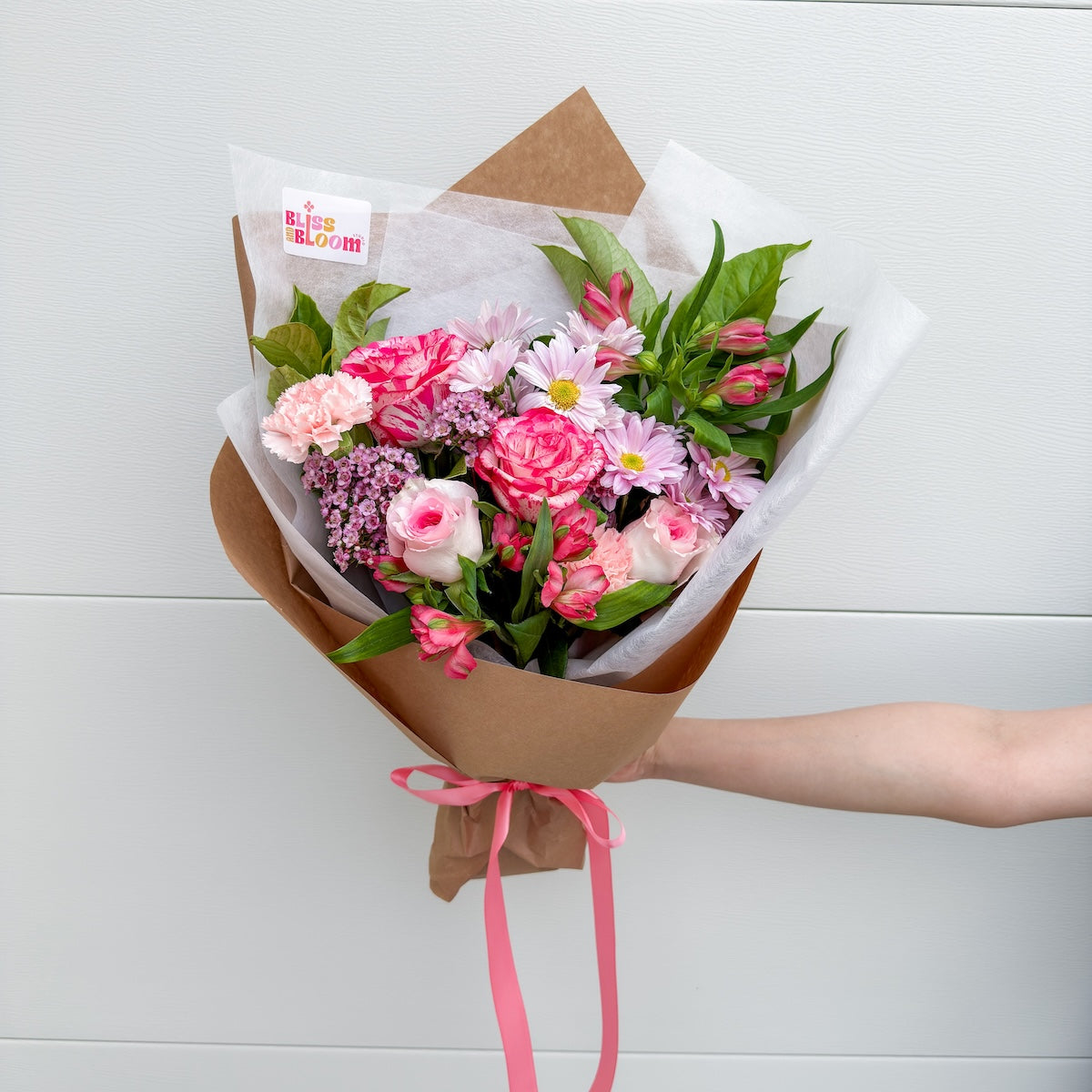 Wrapped double bunch of pink seasonal flowers, styled against a white backdrop by Bliss and Bloom Studio, a Perth florist.