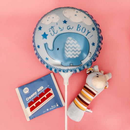 Blue balloon with elephant design and 'it's a boy!' text, next to a packet of Creamy Milk and a small plush rattle | Gift & Flower Delivery Perth