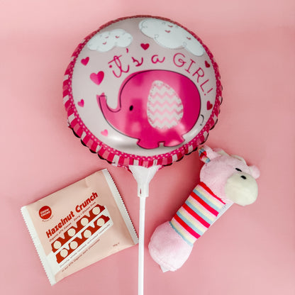 Pink balloon with elephant design, Hazelnut Crunch packet, and plush rattle on pink background | Flowers & Gift Delivery Perth