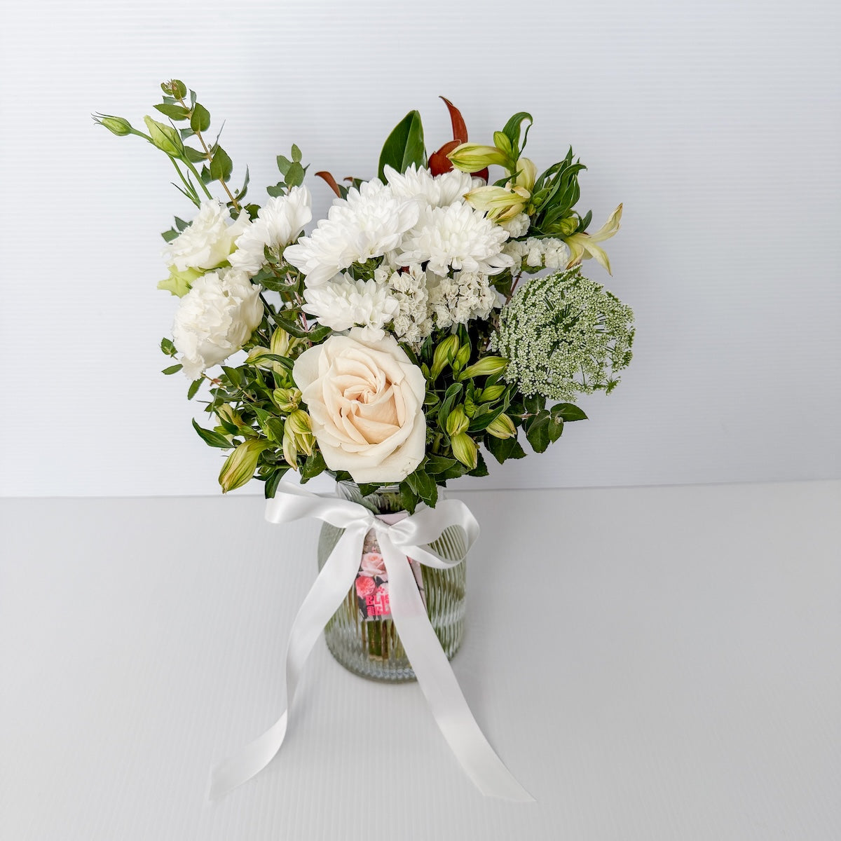 Bouquet of white and light-coloured flowers in a clear glass ribbed vase with a white ribbon |  Sympathy Bunch in Glass Vase Small size | Bliss and Bloom Studio | Perth Flower Delivery