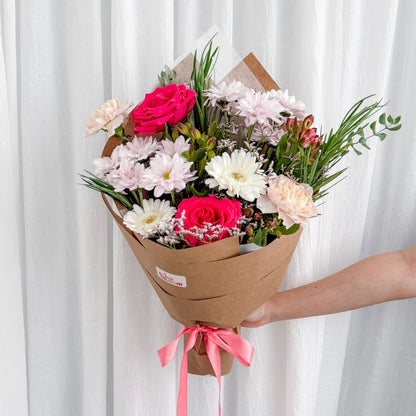 Wrapped double bunch of pink seasonal flowers, styled against a white linen backdrop by Bliss & Bloom Studio, a Perth florist.